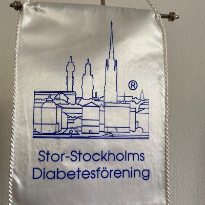 SSDF:s logo med Stockholmsilhuett på ett standar