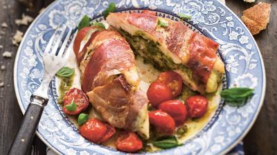 Färserade kycklingfiléer med pesto och mozzarella på en tallrik tillsammans med halverade körsbärstomater
