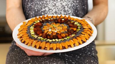 Mammas mandel och chokladkaka med massor av mandel fa som garnering. Närbild på fat som en person håller i.