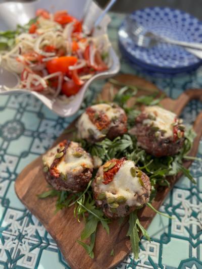 Fyra köttfärsbiffar med mozzarella och tomatsallad upplagda för servering