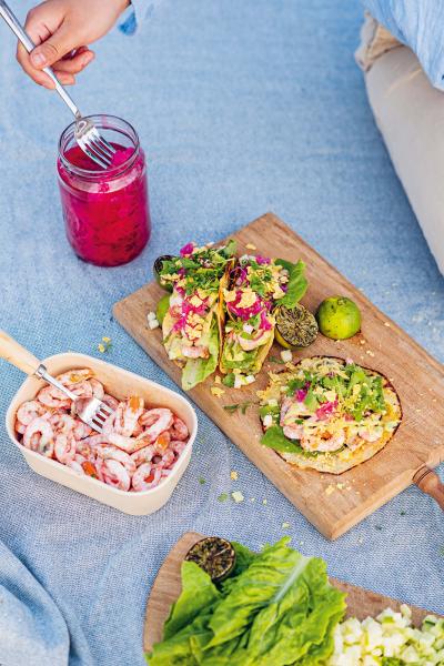 Skärbräda med Tortillabröd med picklad rödlök, Lime och koriandermajonäs, räkor, äpple, jalapeno, sallad, gurka mm på och bredvid picklad rödlök och räkor.