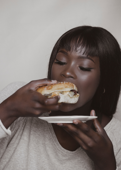Ung kvinna som äter hamburgare